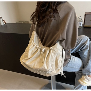 Close-up of a beige large-capacity crossbody bag with drawstring design and textured fabric
