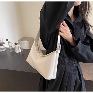 Chic beige PU leather shoulder bag styled with black dress in a modern cafe setting