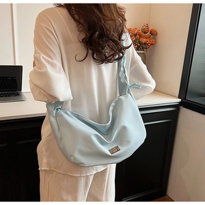 Detail of light blue crescent shoulder bag featuring premium matte fabric and silver logo
