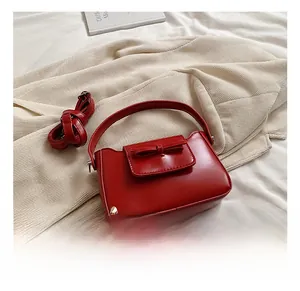Detail of red PU leather bag with decorative bow and detachable shoulder strap