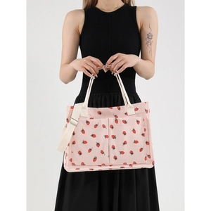Pink corduroy tote bag with strawberry print and multiple pockets shown by a model