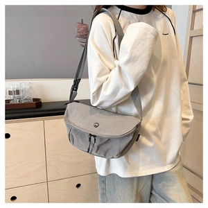 Detail of grey washed fabric crossbody bag with buckle flap and wide shoulder strap