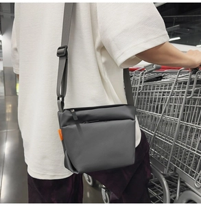 Close-up of waterproof dark grey crossbody bag with adjustable strap and orange side label