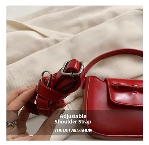 Detail show of adjustable red PU leather shoulder strap with silver buckle on handbag