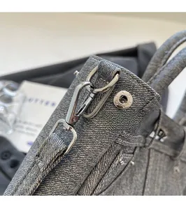 Détails des crochets en métal argenté et boucles sur la sacoche en denim gris texturé