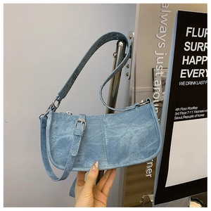 Vue détaillée du sac à bandoulière en denim bleu clair avec œillets argentés sur la sangle