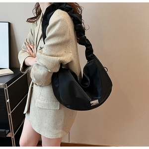 Detail of black crescent shoulder bag featuring a pleated cloud-style strap and metal logo