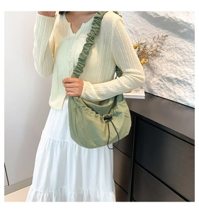 Detail view of light green crossbody bag with ruched strap and drawstring closure