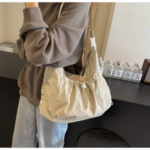 Detail view of nylon crossbody bag featuring adjustable side drawstrings and plastic buckle