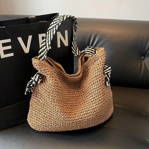 Sac à bandoulière en paille minimaliste avec anses rayées noir et blanc sur un canapé