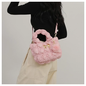 Détail du sac bandoulière matelassé rose avec boucle nœud doré et pompon doux assorti