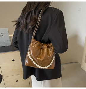 Detail of dark brown quilted PU leather bag with pearls and chain strap on shoulder