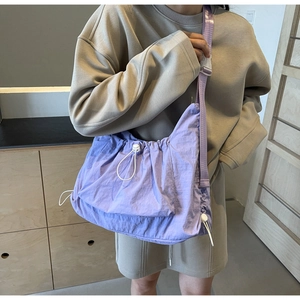 Detail view of lavender nylon crossbody bag featuring adjustable drawstring and wide strap