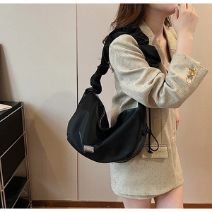 Detail view of black nylon hobo bag with trendy pleated cloud strap and silver logo plate