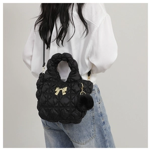 Détail du sac matelassé noir avec fermoir noeud doré et pompon en peluche doux