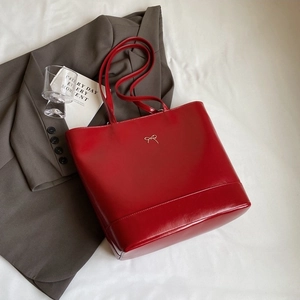Elegant red PU leather tote bag with gold bow decoration on a minimalist white surface