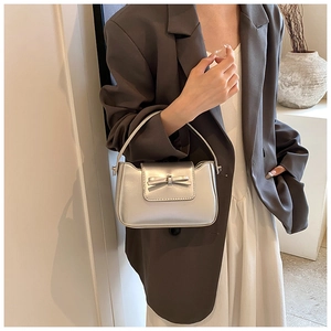 Detail of silver metallic PU handbag featuring a bow ornament on the front flap