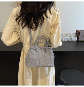 Détail du sac bandoulière gris texture denim avec fermoir tournant et deux poignées