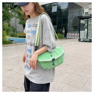 Detail of light green waterproof nylon crossbody bag with adjustable strap and dual zippers