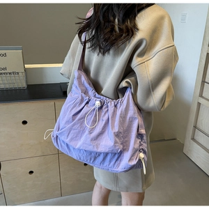 Detail of light purple nylon crossbody bag featuring drawstring closure and adjustable cord lock