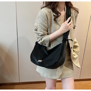 Detail of a chic black half-moon PU crossbody bag with silver logo and drawstring strap