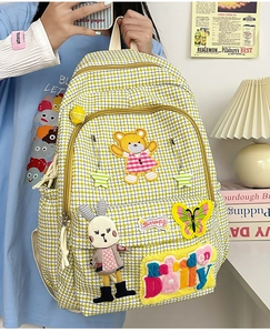 Close-up of yellow plaid backpack with cute teddy bear embroidery and cartoon patches