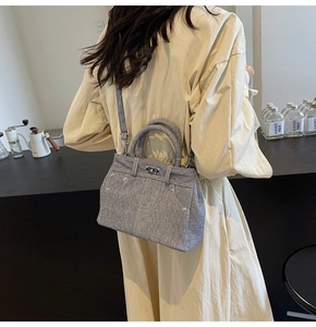 Détail du sac bandoulière en denim gris avec fermoir rotatif en métal et rivets chic