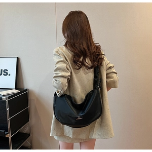 Close-up of black PU leather crescent crossbody bag with metallic logo and wide strap