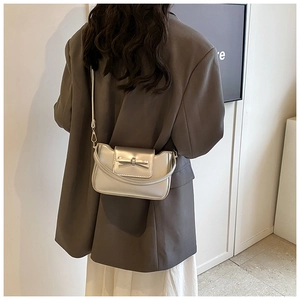 Close-up of silver PU leather crossbody bag with metallic bow detail on model's back