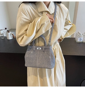 Détail du sac bandoulière en denim bleu clair avec clous argentés et fermoir rotatif