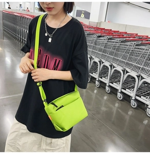 Neon green crossbody bag worn by model in a stylish urban industrial setting