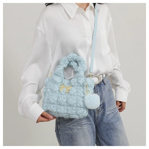 Détail du sac bandoulière en nylon matelassé bleu clair avec nœud doré et pompon doux