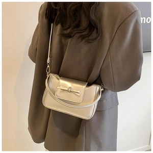 Silver PU leather crossbody bag with bow detail worn by a model in casual blazer