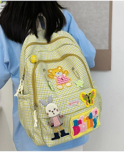 Detail view of yellow plaid backpack featuring cute cartoon bear and bunny embroidery patches