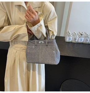 Détail d'un sac à main en jean bleu avec fermoir rotatif argenté et rivets décoratifs
