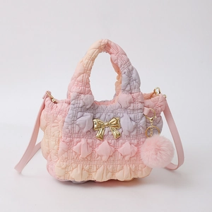 Détail d'un sac nuage en nylon dégradé avec nœud doré et pompon rose en peluche