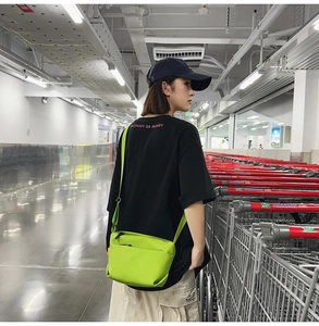 Detail of neon green crossbody nylon bag with double zippers in a street style setting