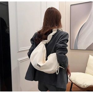 Chic cream PU crossbody bag with ruffled strap shown on model in a modern interior setting