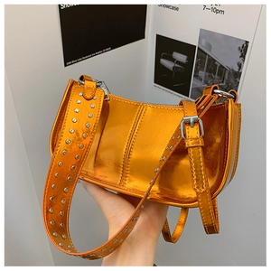 Détail du sac orange métallisé avec clous argentés sur la bandoulière et fini brillant