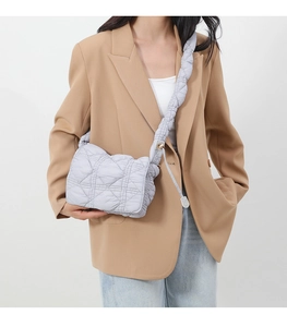 Detail of light gray quilted nylon crossbody bag featuring a unique thick pleated strap design