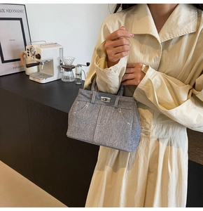 Détail du sac bandoulière en denim avec fermoir rotatif et coutures à rivets vintage