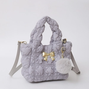 Détail du sac en nylon matelassé lavande avec nœud doré et pendentif pompon doux