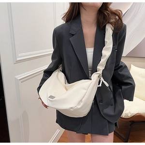 Close-up of cream white PU leather crescent bag with wide pleated strap and metal detail