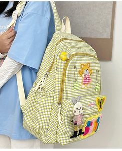 Detail view of nylon backpack featuring yellow houndstooth pattern and cartoon patches
