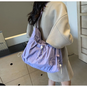 Detail view of purple ruched nylon crossbody bag with adjustable white drawstring feature