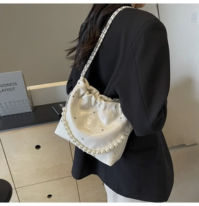 Detail view of quilted white shoulder bag with pearl chain and silver stud accents