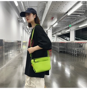 Detailed close-up of a neon green crossbody bag with smooth fabric and orange side label