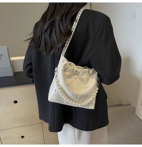 Detail of white glossy PU handbag featuring quilted patterns and pearl chain strap