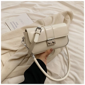 Minimalist cream white patent leather crossbody bag with silver buckle on soft fabric