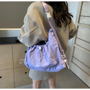 Detail view of purple drawstring crossbody bag with adjustable strap and textured nylon fabric